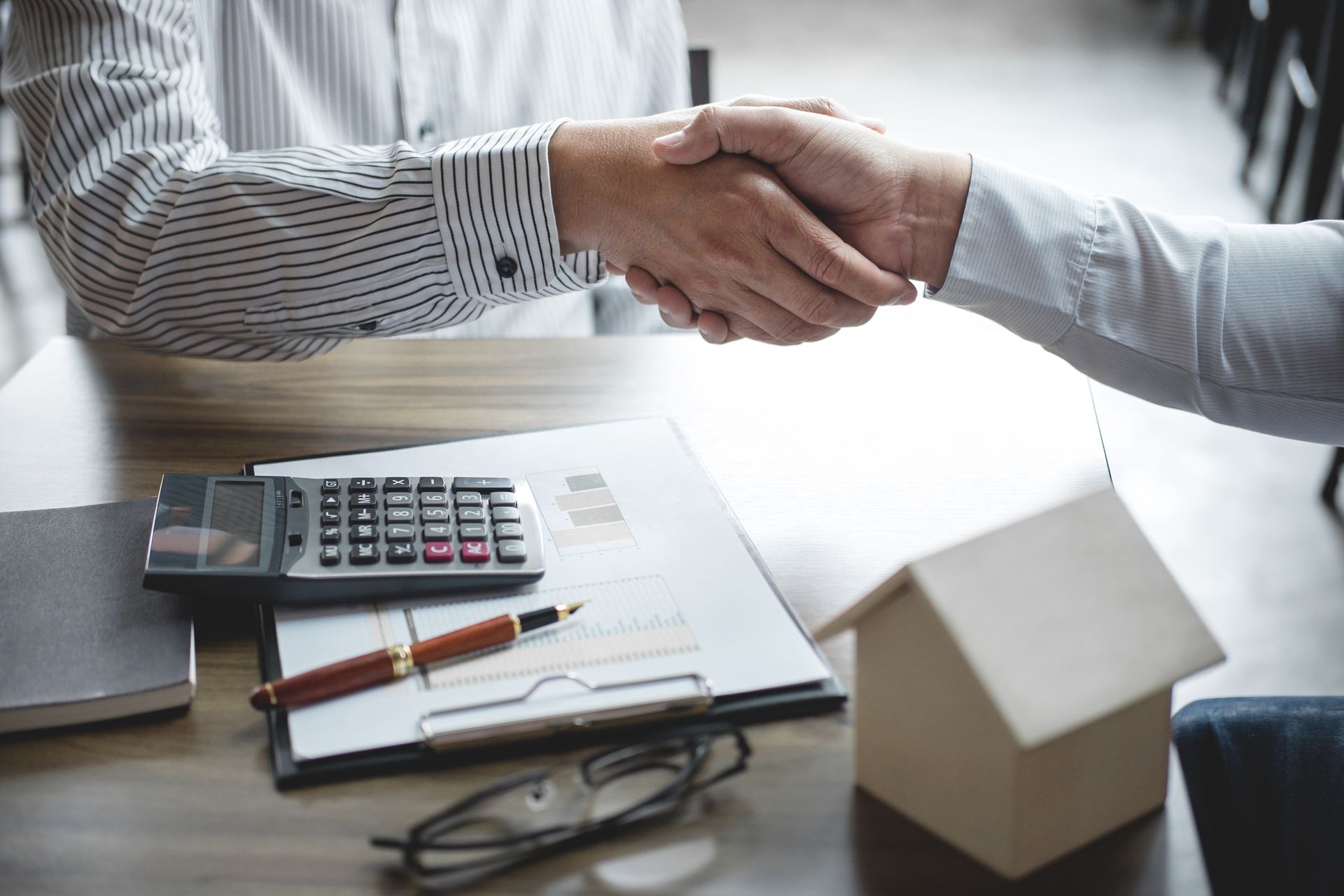 Estate planning attorney shaking hands with client after signing estate documents in office.