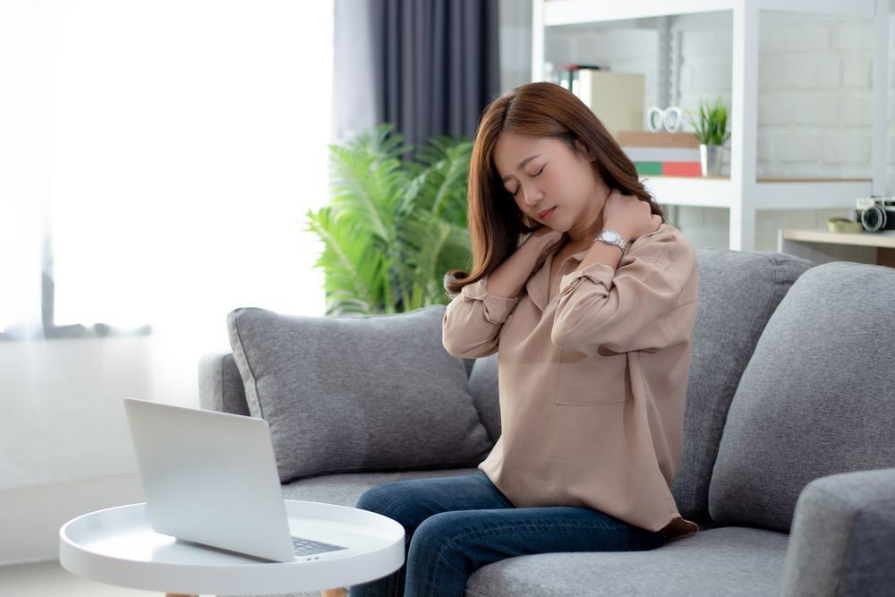 a woman is sitting on a couch in front of a laptop computer .