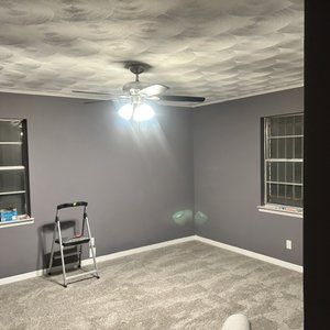 A room with a ceiling fan and a ladder in it.