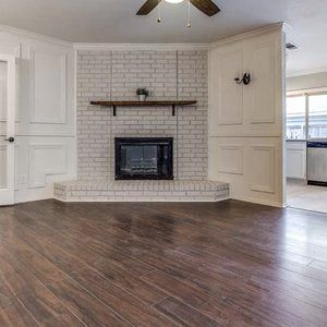 A living room with a fireplace and a ceiling fan.