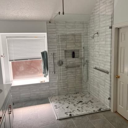 A bathroom with a walk in shower and a window.