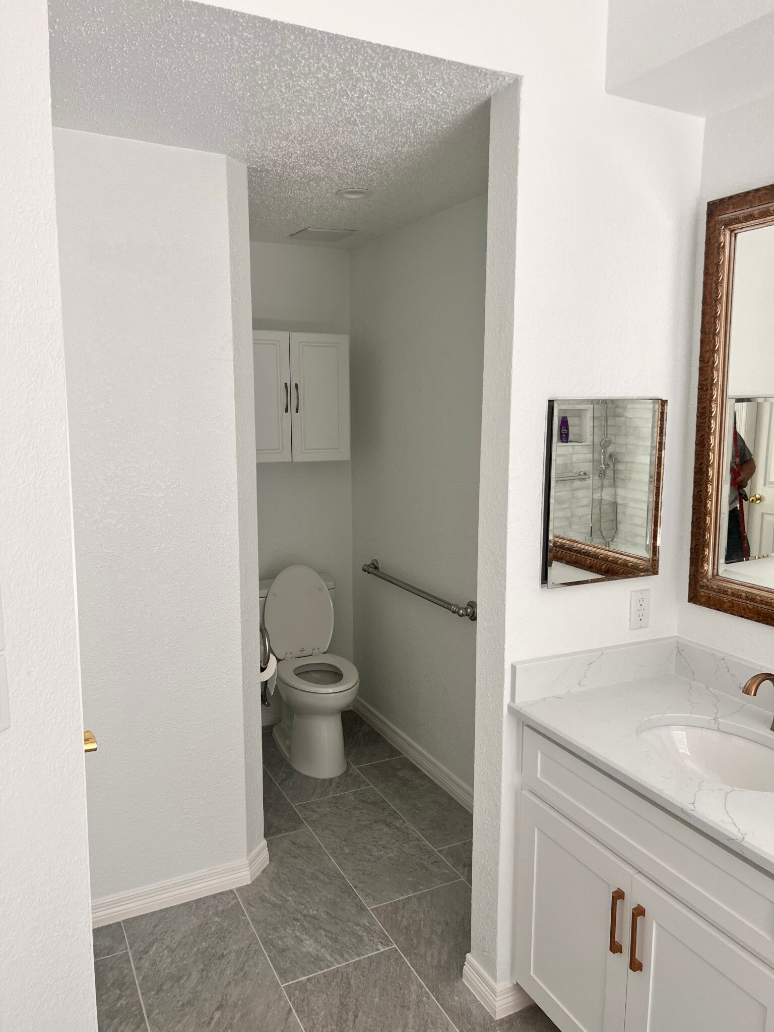 A bathroom with a toilet , sink and mirror.