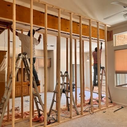A man is standing on a ladder in a room under construction