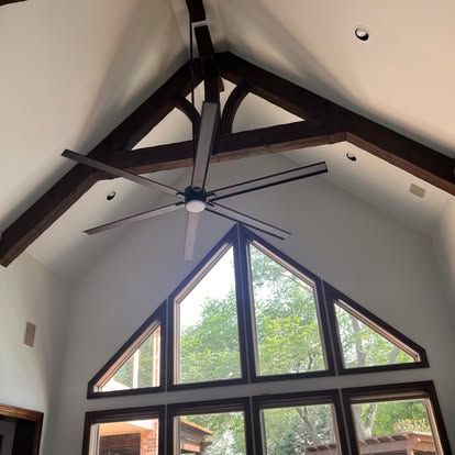 A ceiling fan is hanging from the ceiling of a room with a lot of windows