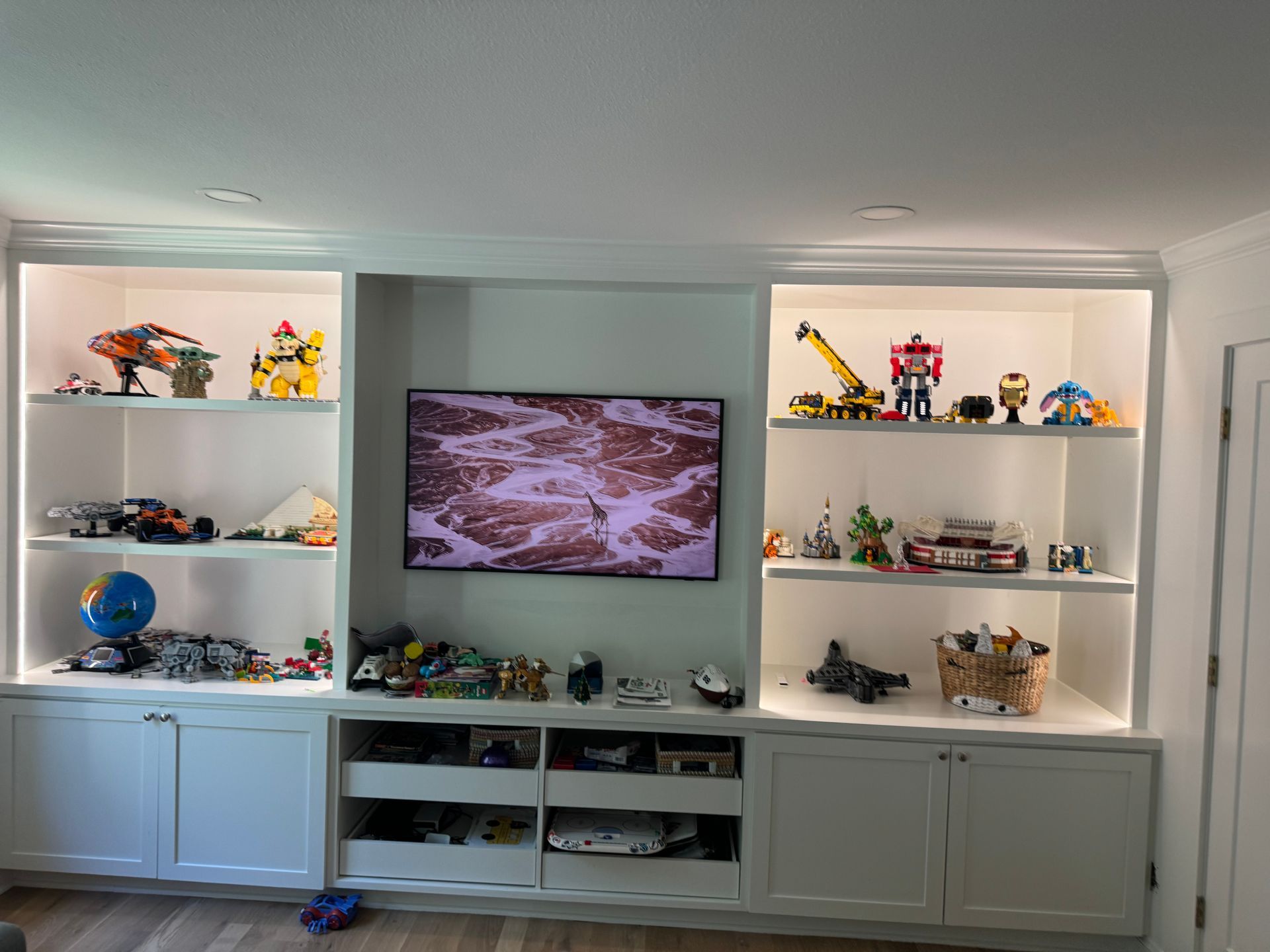 Built-in shelves with toys and a wall-mounted TV in a bright living room