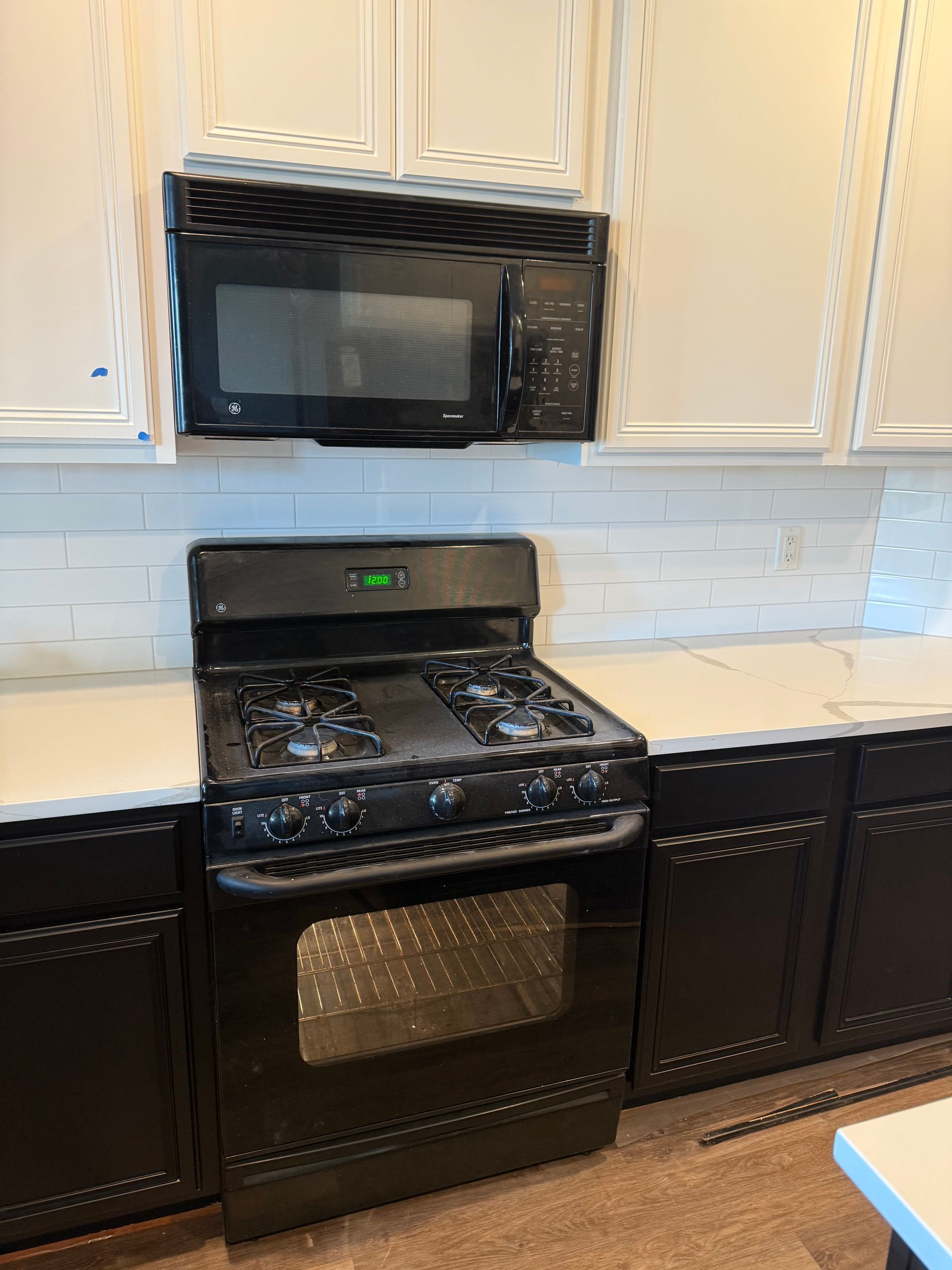 A black stove and microwave are in a kitchen.