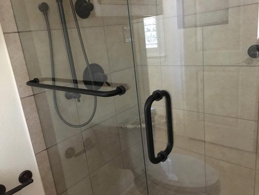 A bathroom with a toilet and a shower with a black handle