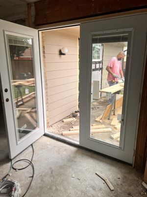 A man is working on a patio door in a room.