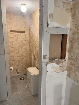 A bathroom is being remodeled with drywall and a toilet.