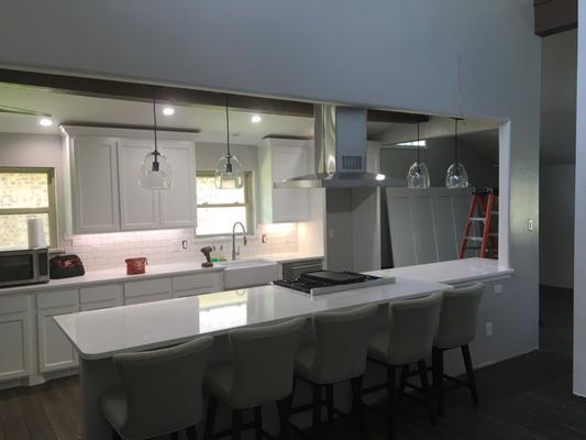 A kitchen with white cabinets , a large island , and a stove.