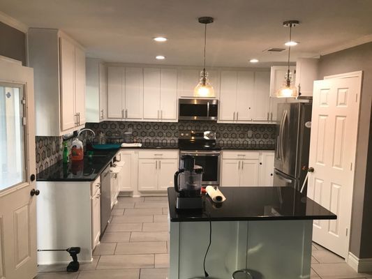A kitchen with white cabinets and black counter tops