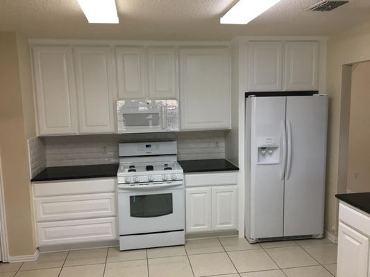 A kitchen with a stove , refrigerator and microwave