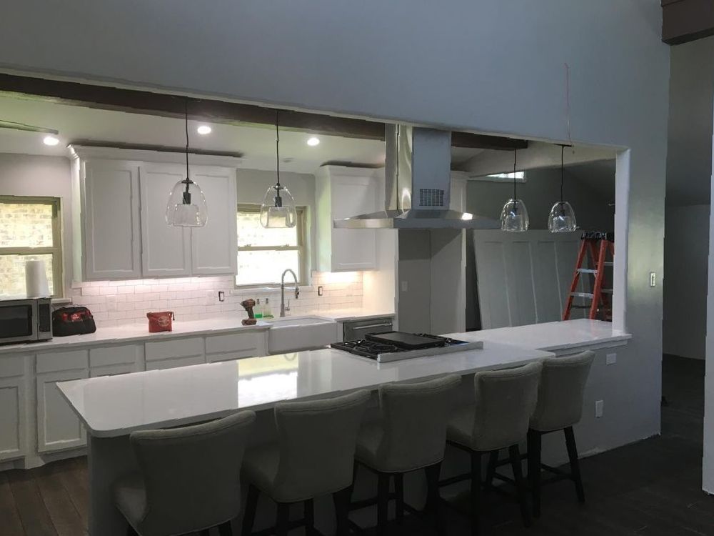 A kitchen with white cabinets , a large island , and a stove.