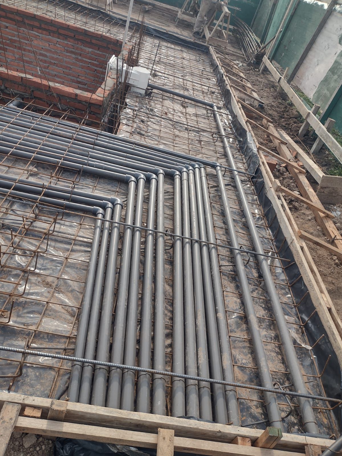Obra en construcción con tuberías de PVC colocadas sobre una base de hormigón.