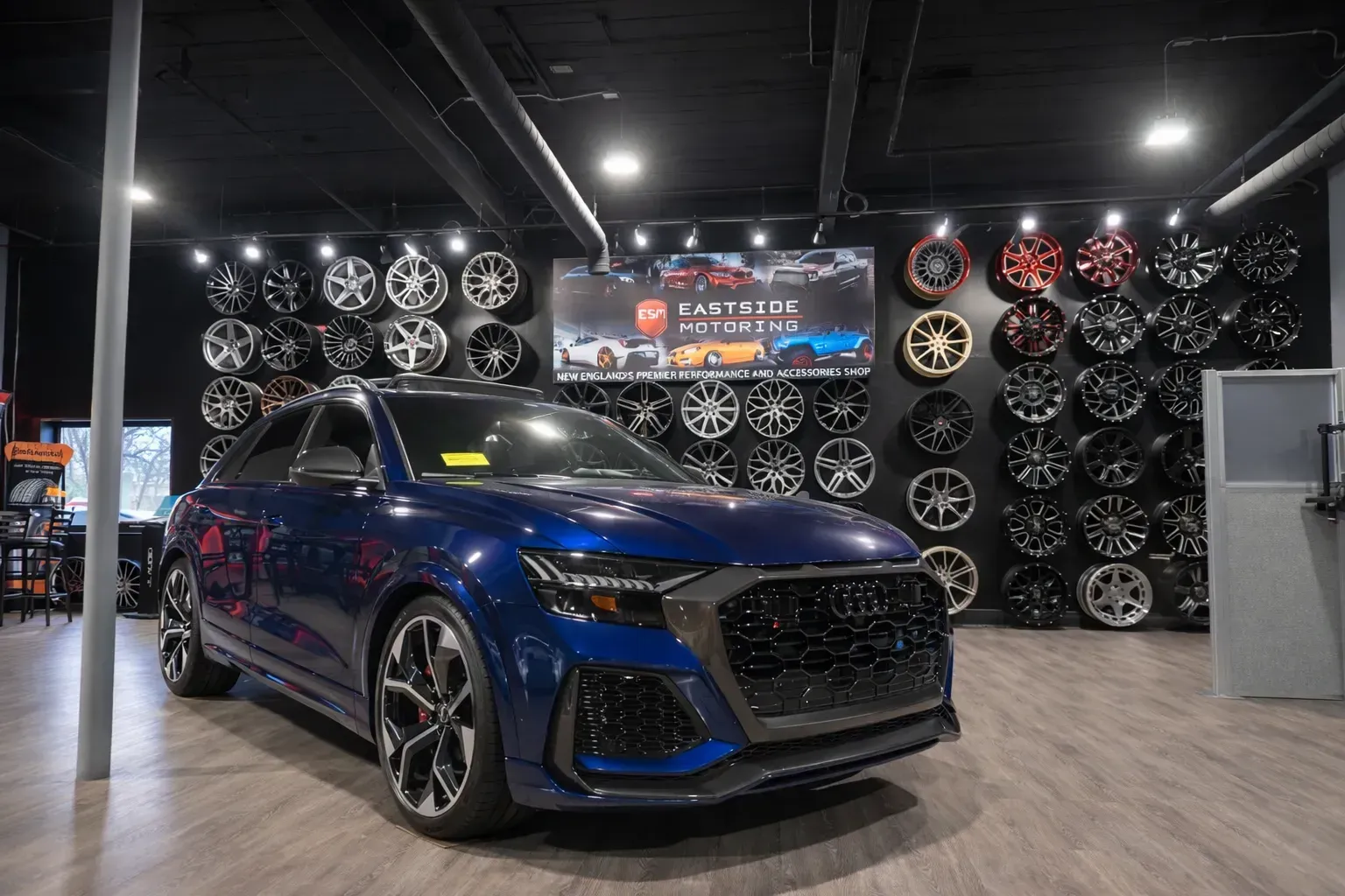 Blue Audi SUV parked in a showroom with wheels displayed on a black wall | Eastside Motoring