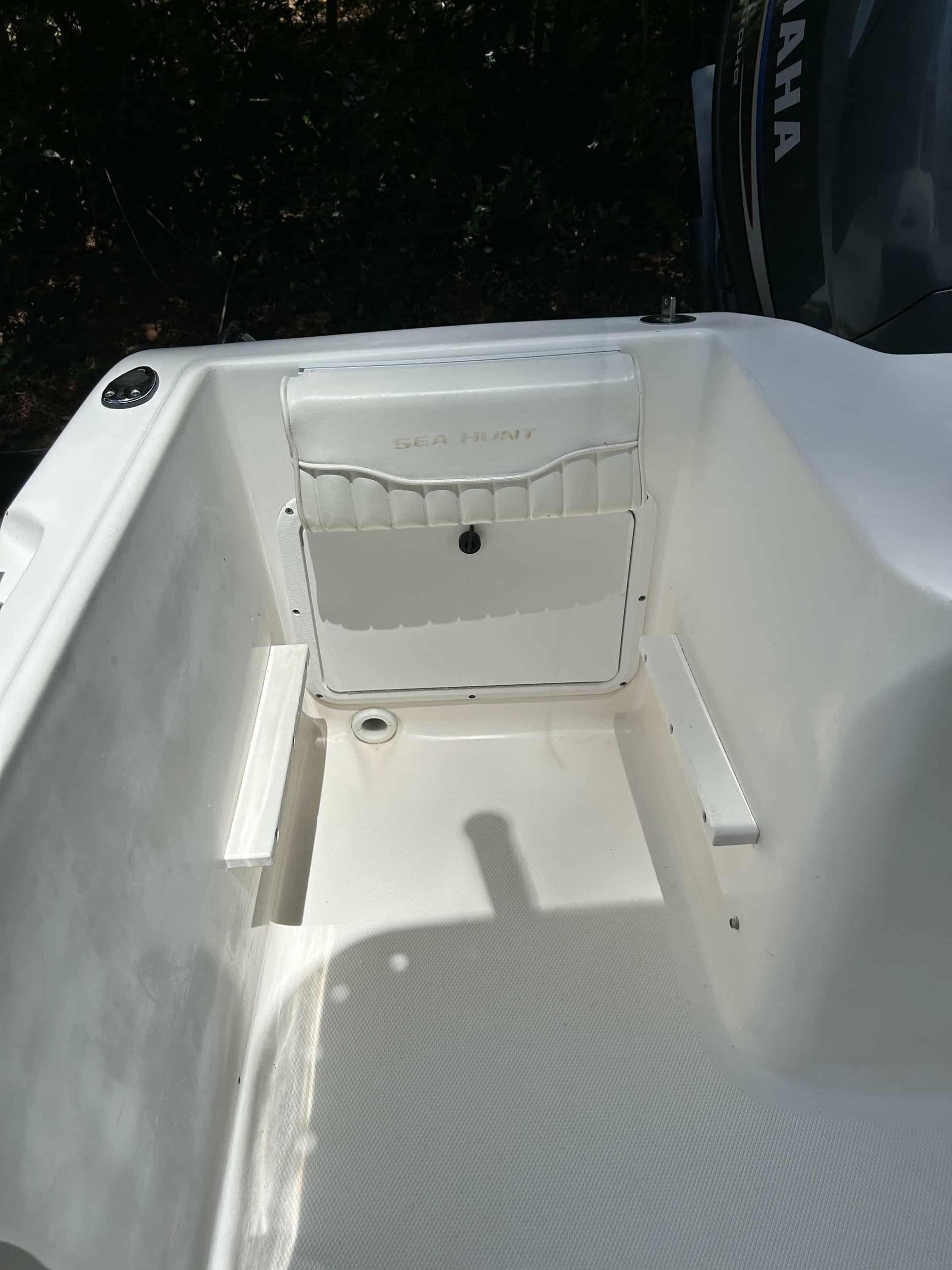 White boat interior with storage compartment and ribbed floor.