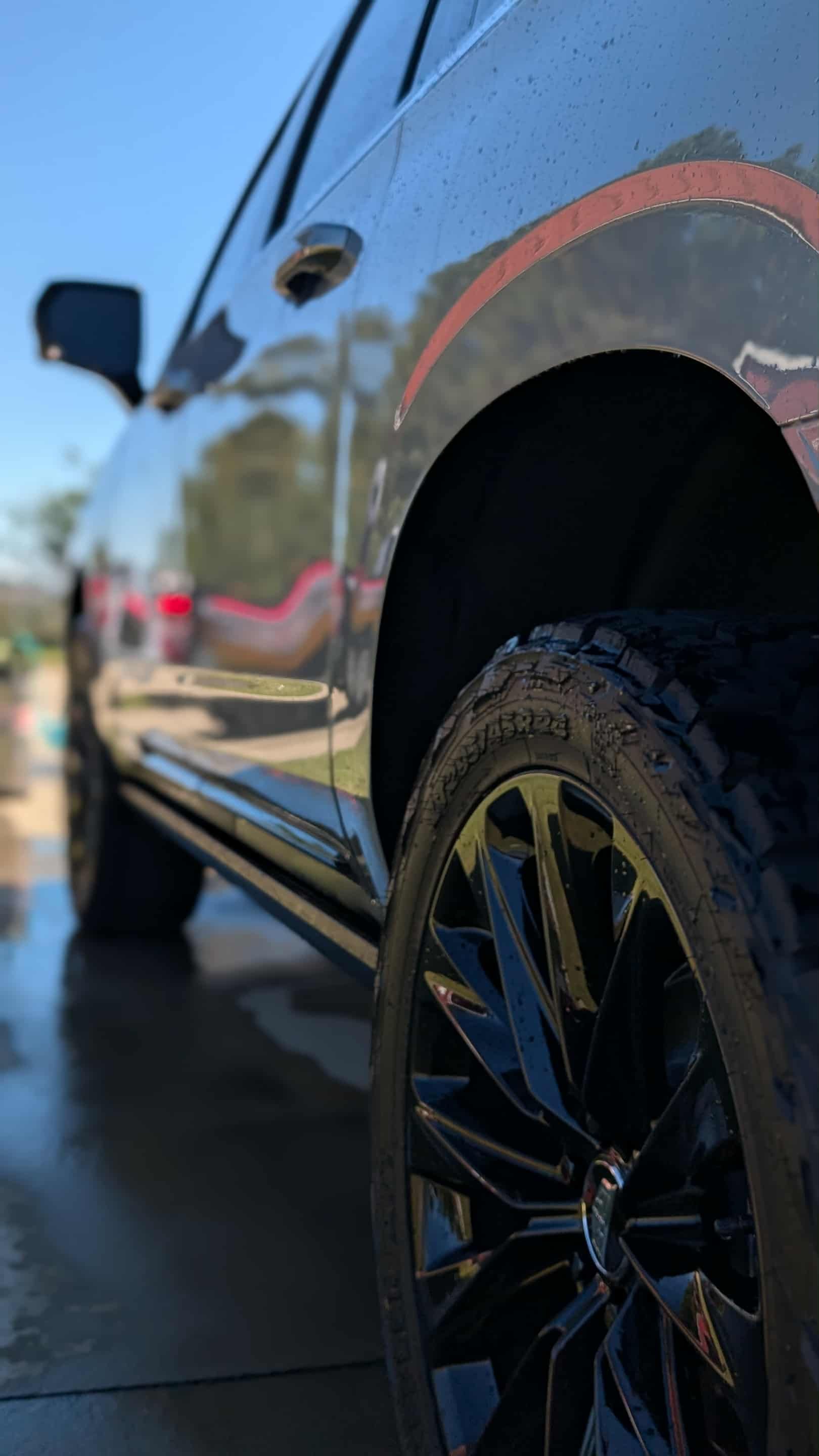 Black SUV with shiny black wheels, parked outside on a sunny day.