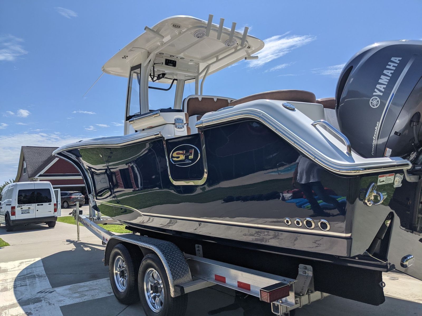 Dark blue motorboat on a trailer, under a bright blue sky.
