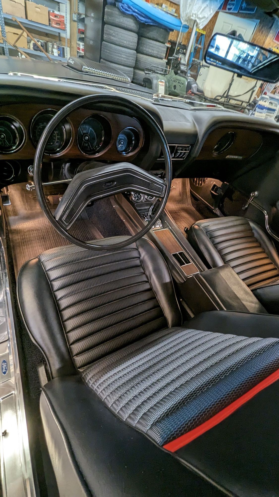 Interior view of a classic black muscle car. Black and gray seats, steering wheel, and dashboard.