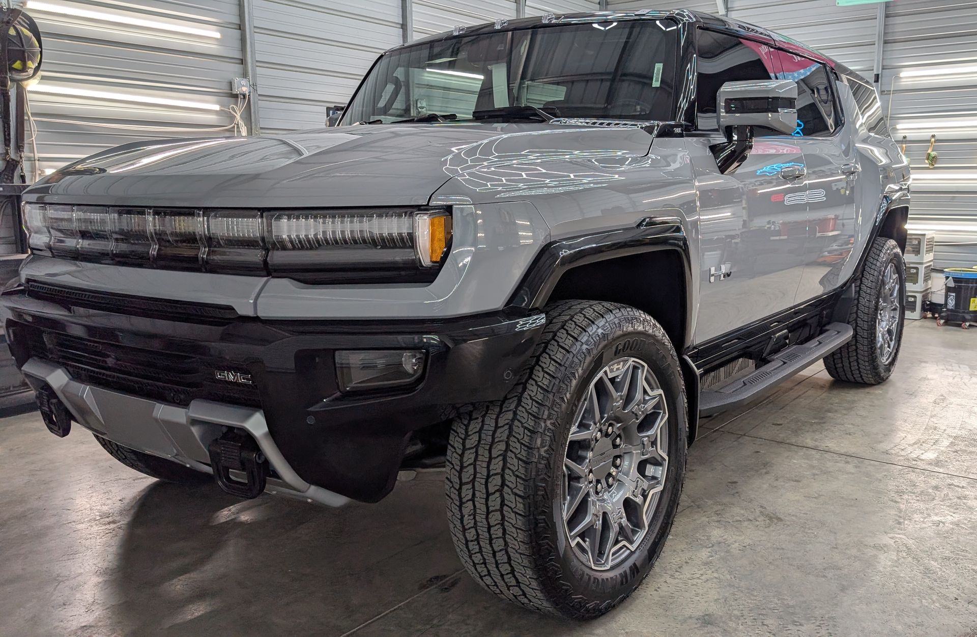 Gray Hummer EV SUV parked indoors. Front view. Chrome wheels.