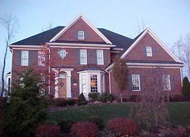 A large brick house with a black roof is sitting on top of a hill.