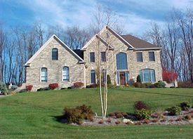 A large stone house is sitting on top of a lush green hillside.