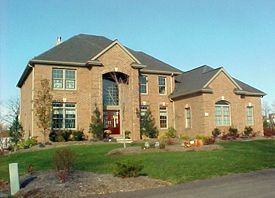 A large brick house with a gray roof and a red door