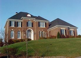 A large brick house sits on top of a lush green hillside.