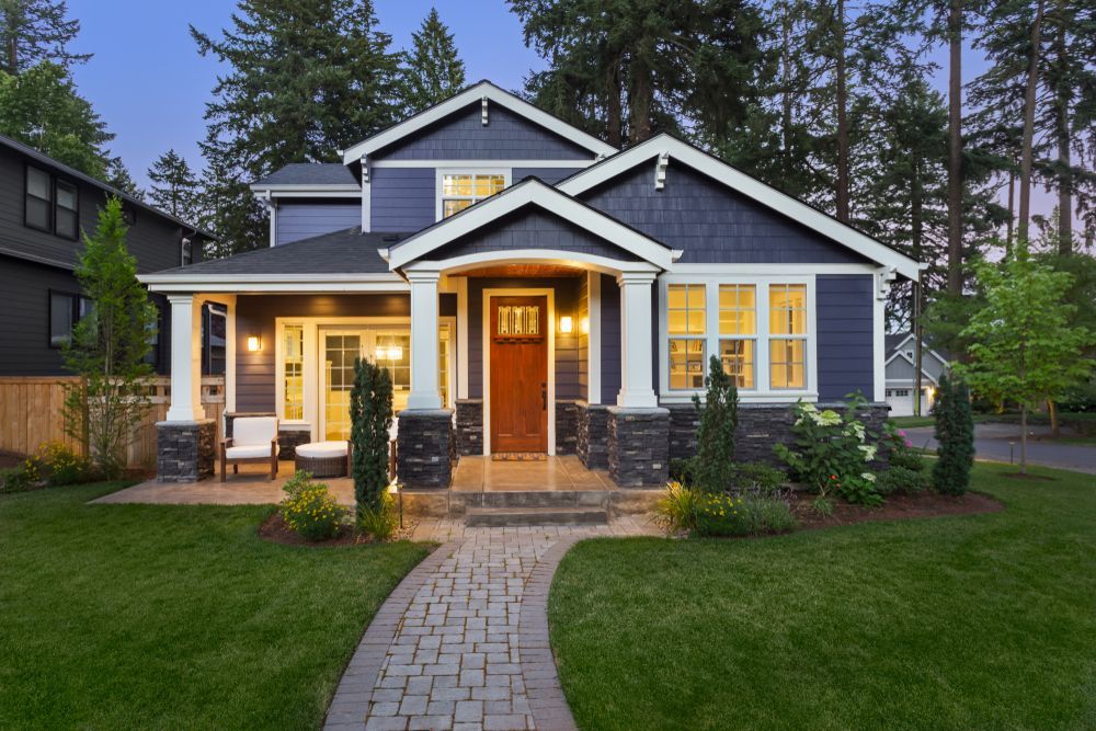 A large blue and white house with a brick walkway leading to it.