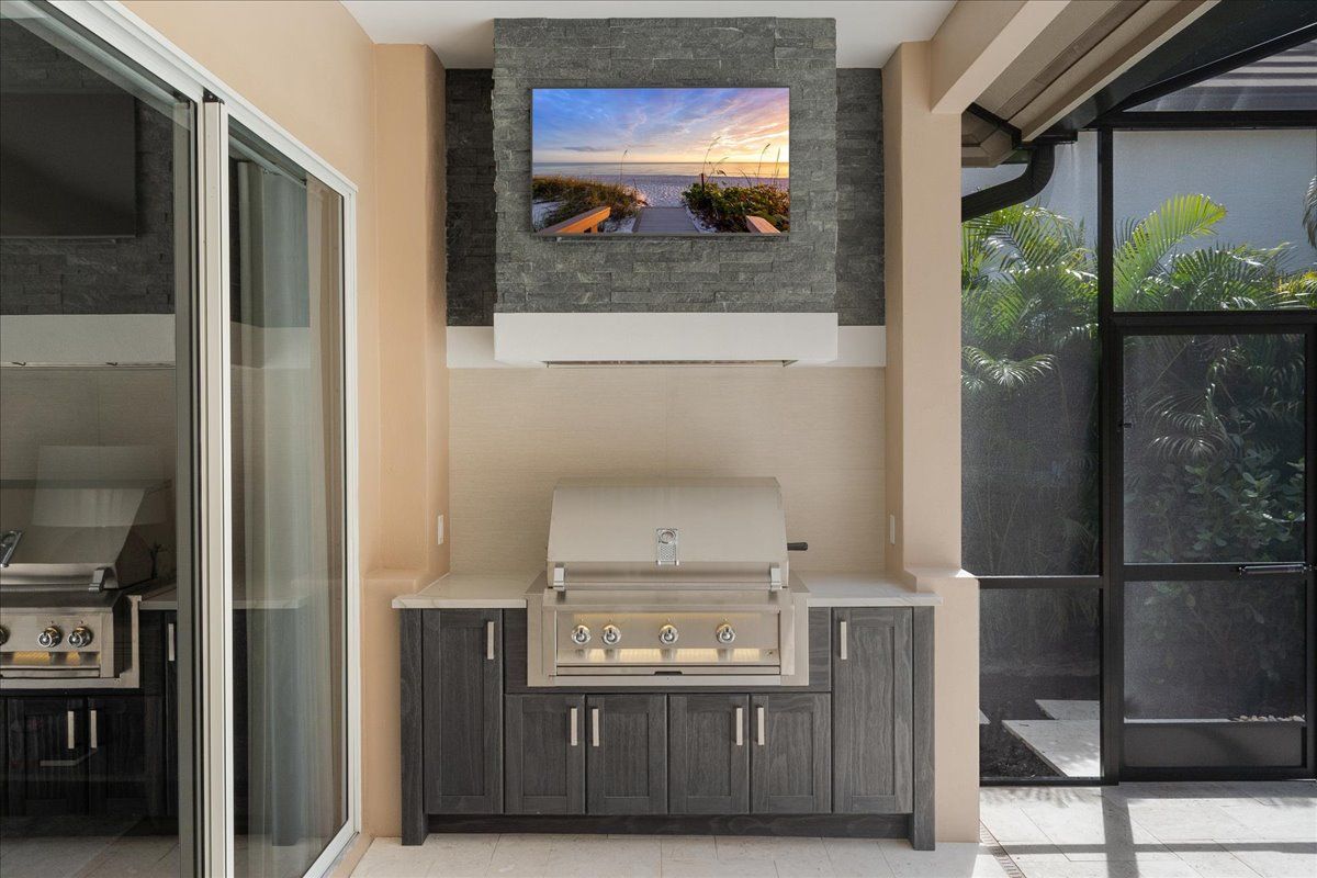 A kitchen with a grill and a flat screen tv hanging from the ceiling.