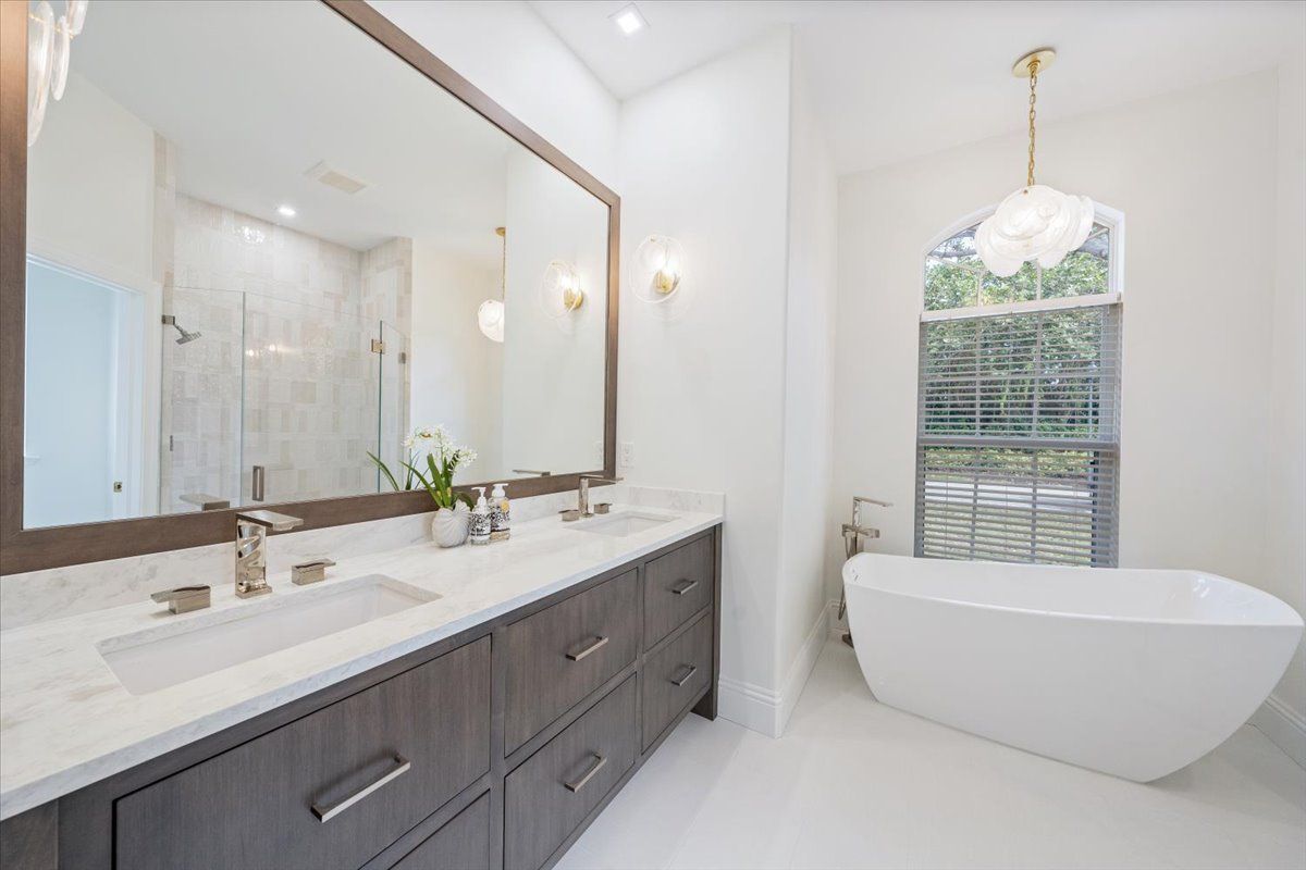 A bathroom with two sinks, a tub and a large mirror.