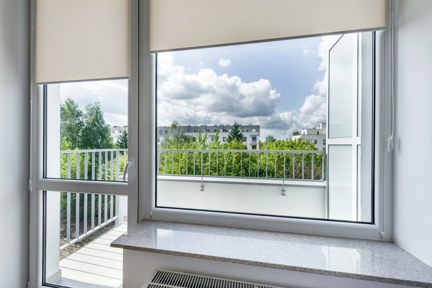 There is a window with blinds on it and a balcony in the background.