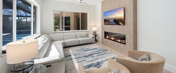 A living room with a couch, chair, television and fireplace.