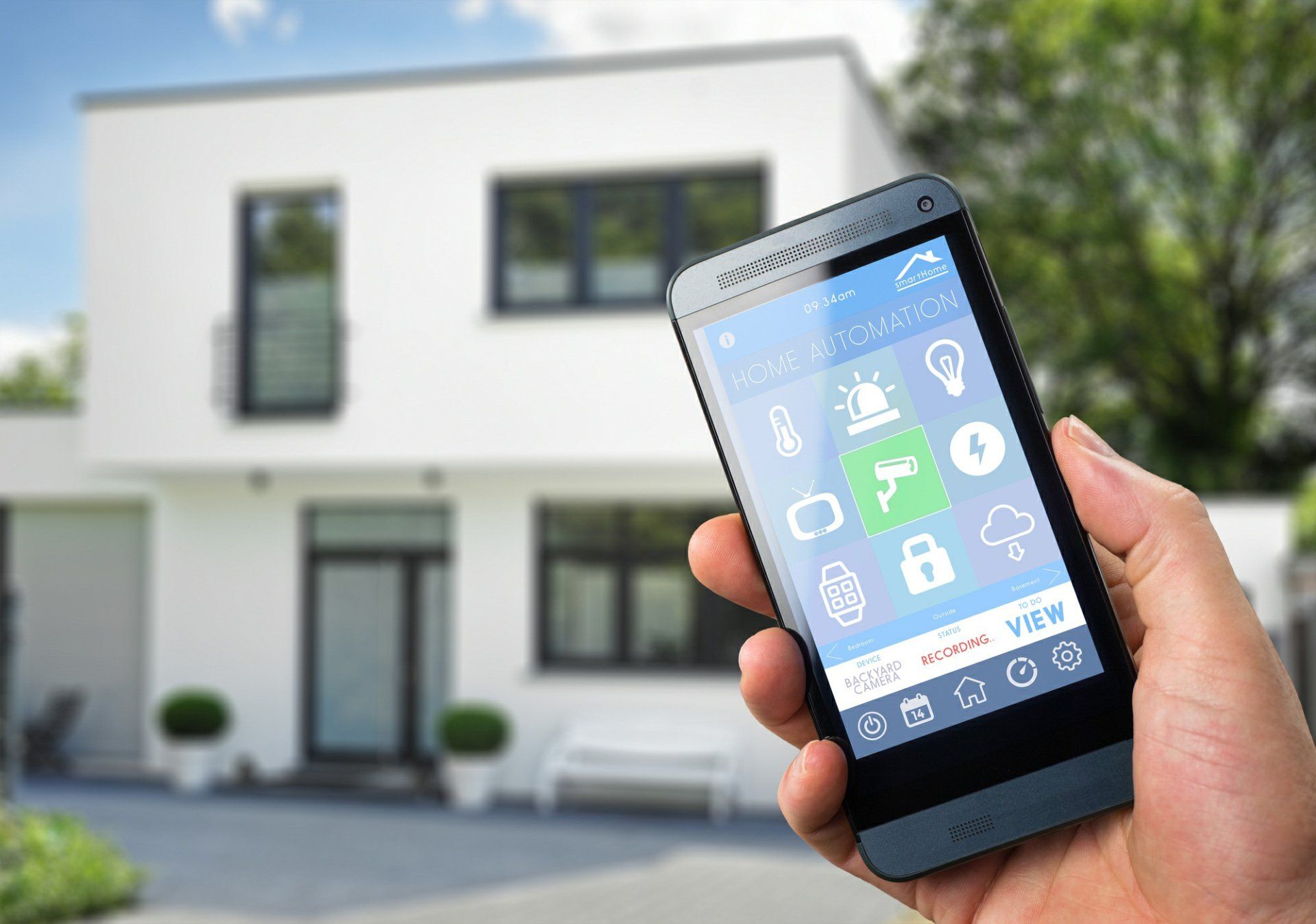 A person is holding a smart phone in front of a house.