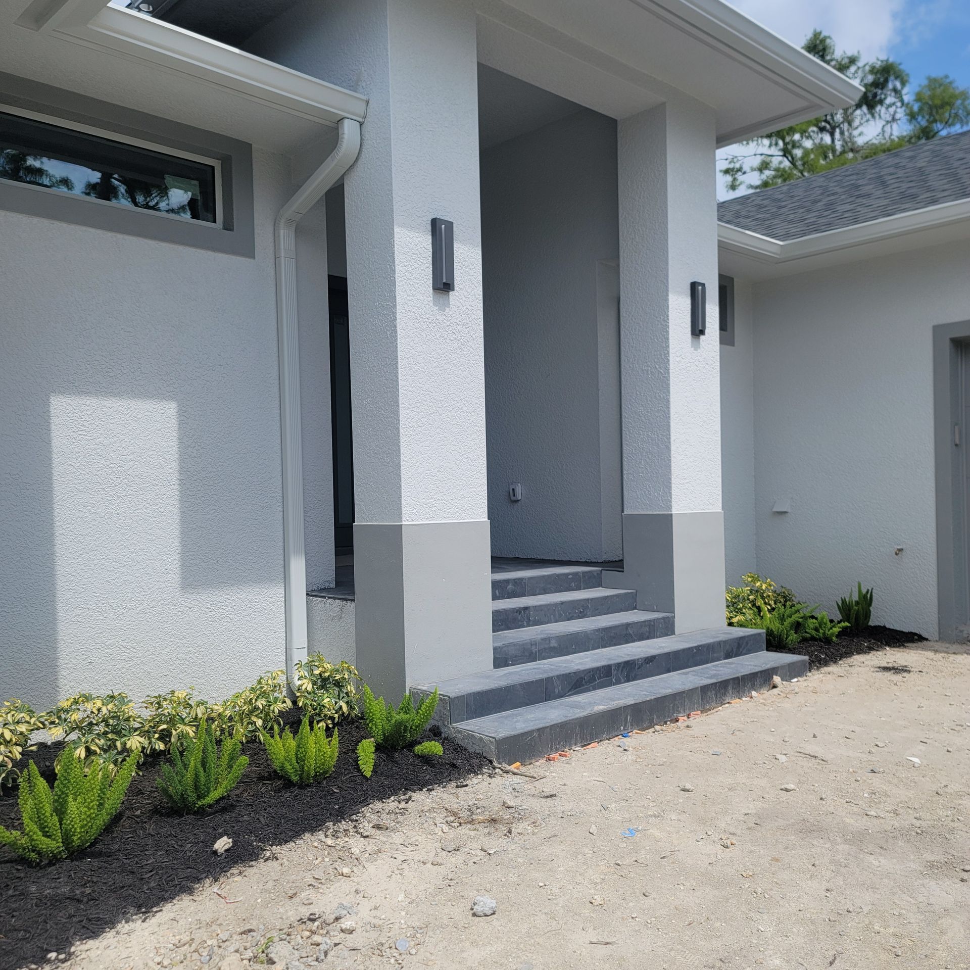 A white house with stairs leading up to the front door.