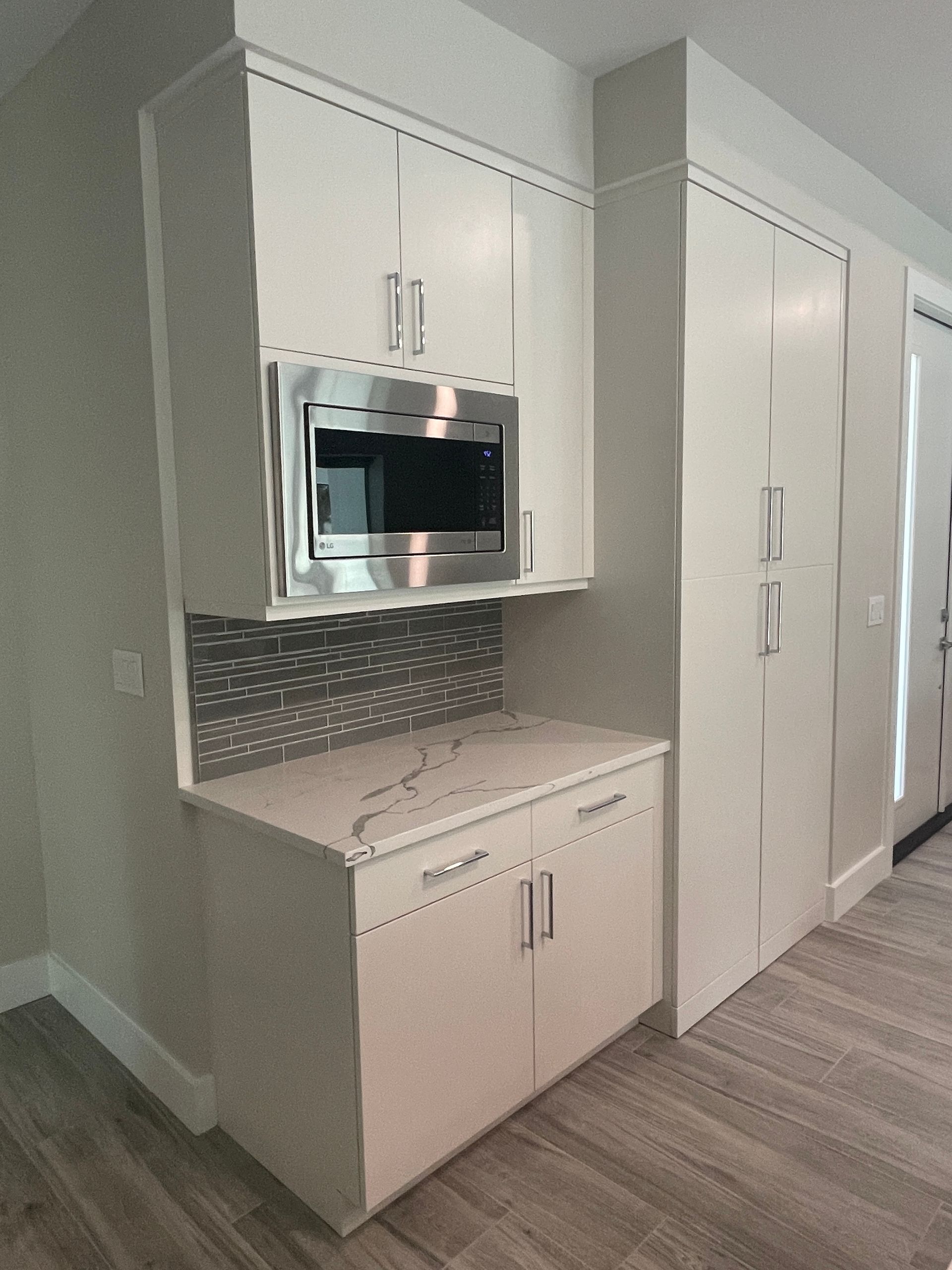 A kitchen with white cabinets and a stainless steel microwave.