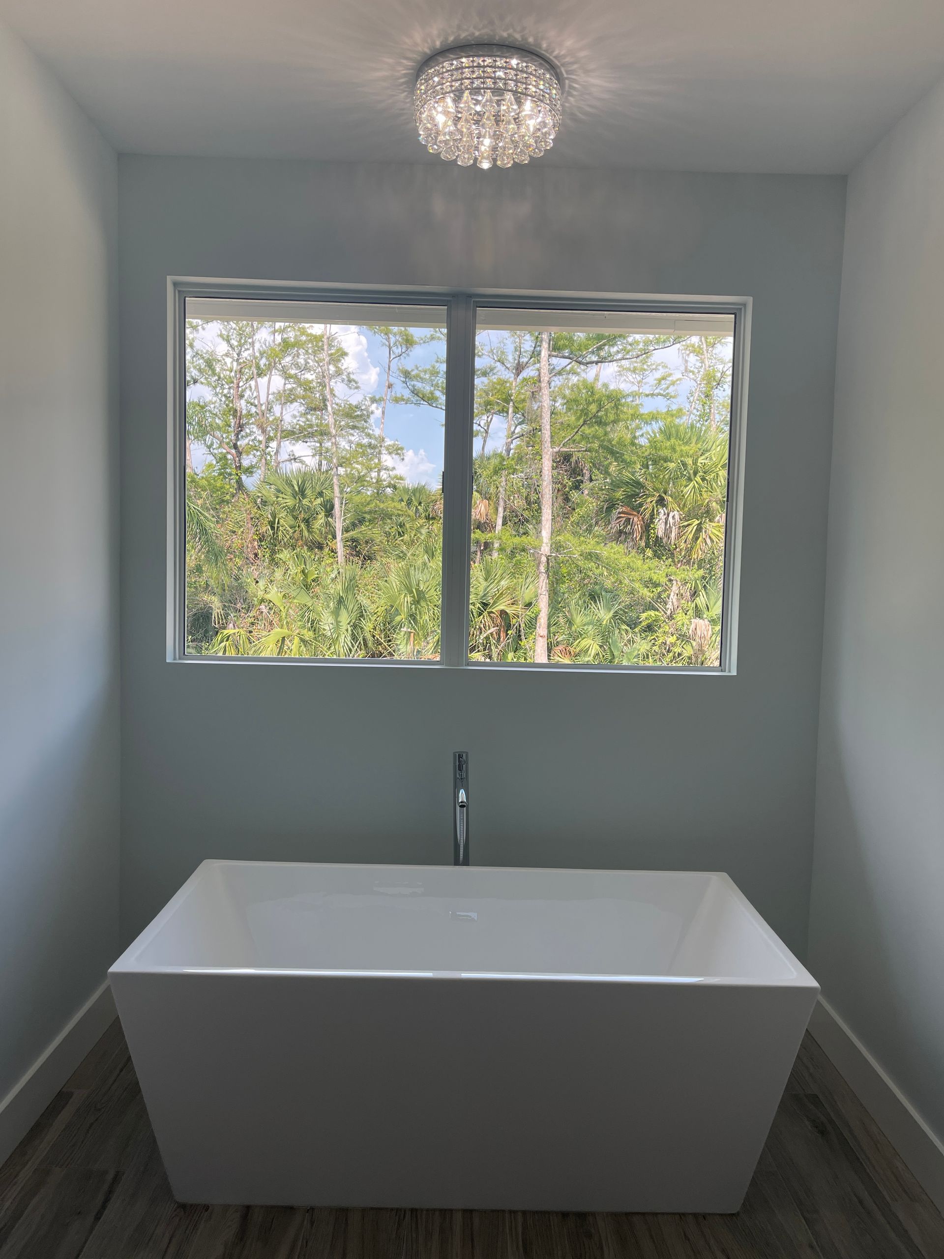 A bathroom with a bathtub and a window with trees in the background.