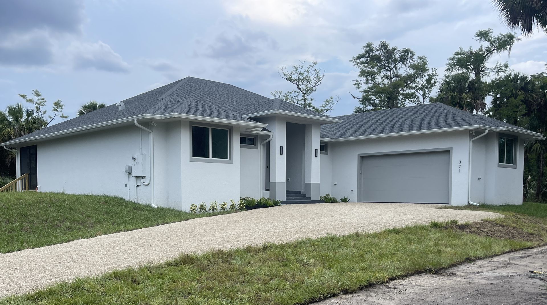 A white house with a garage and a driveway in front of it.
