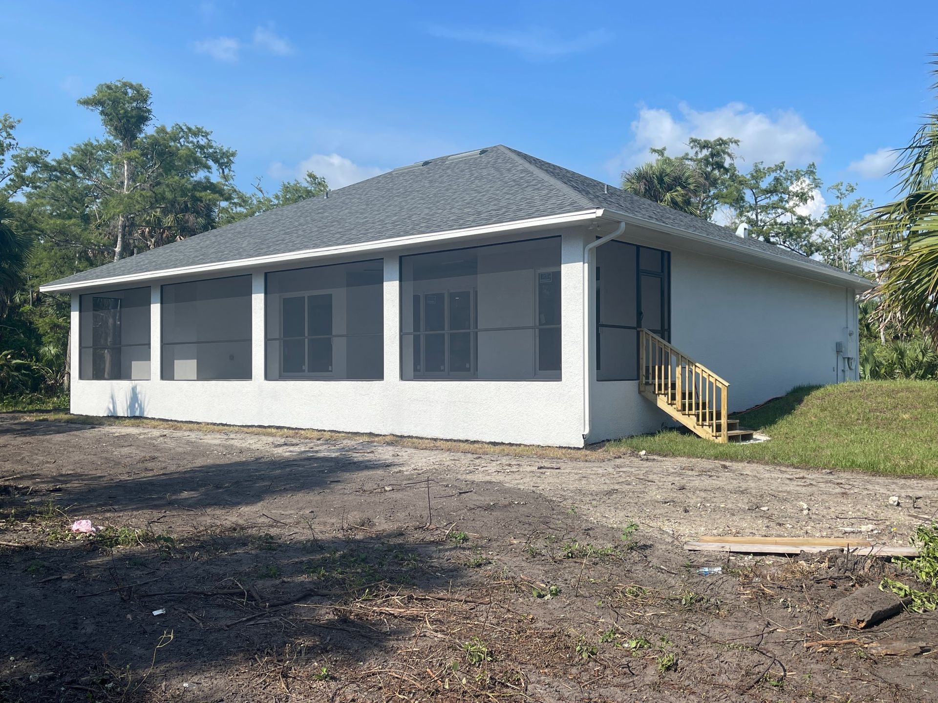 A white house with a screened in porch and stairs.