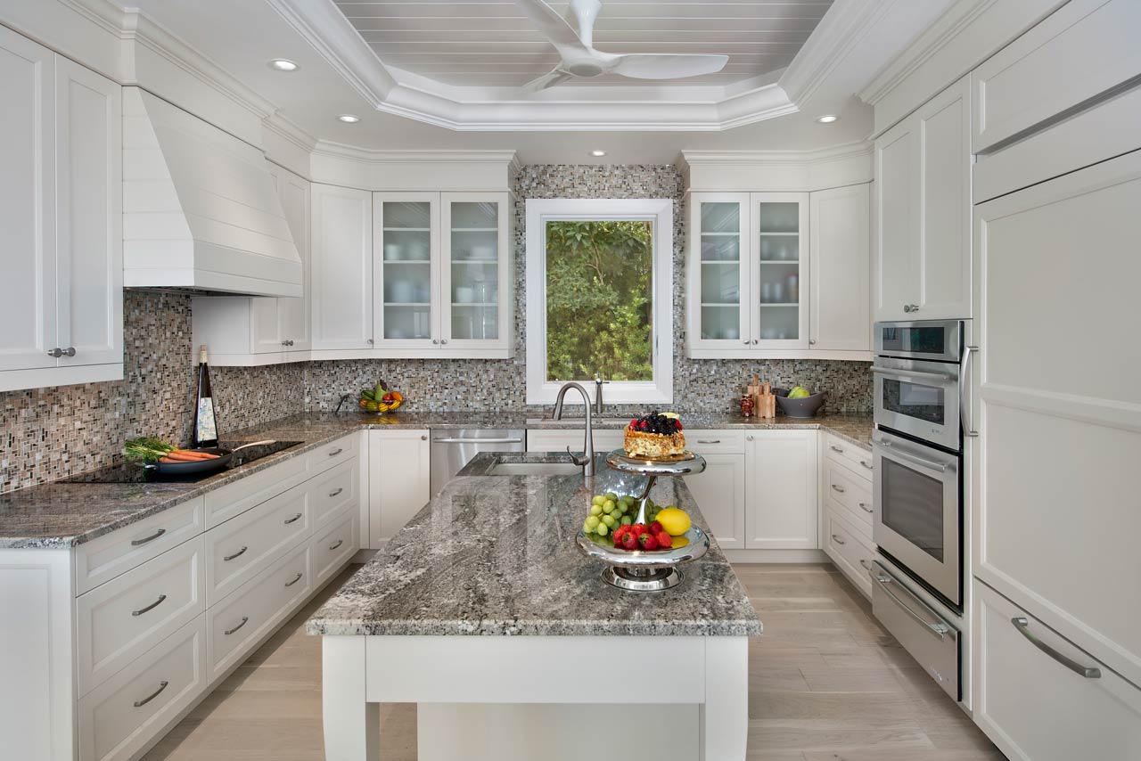 A kitchen with cabinets, granite counter tops, stainless steel appliances and a large island.