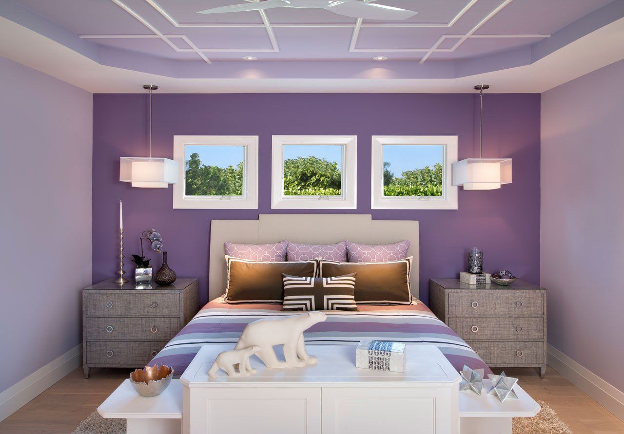 A bedroom with purple walls and a bed.