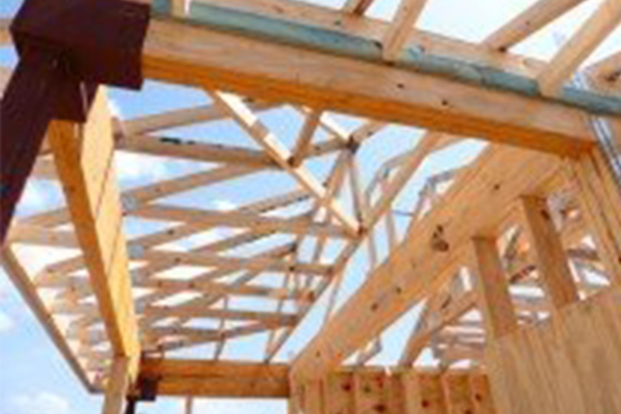 A wooden structure is being built with a blue sky in the background.