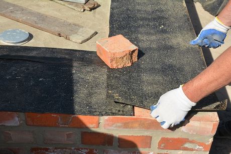 a person with gloves and gloves on working on a brick wall