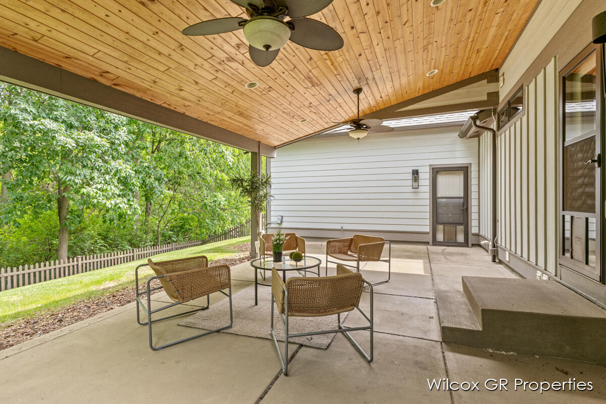 A porch with a table and chairs and a ceiling fan.