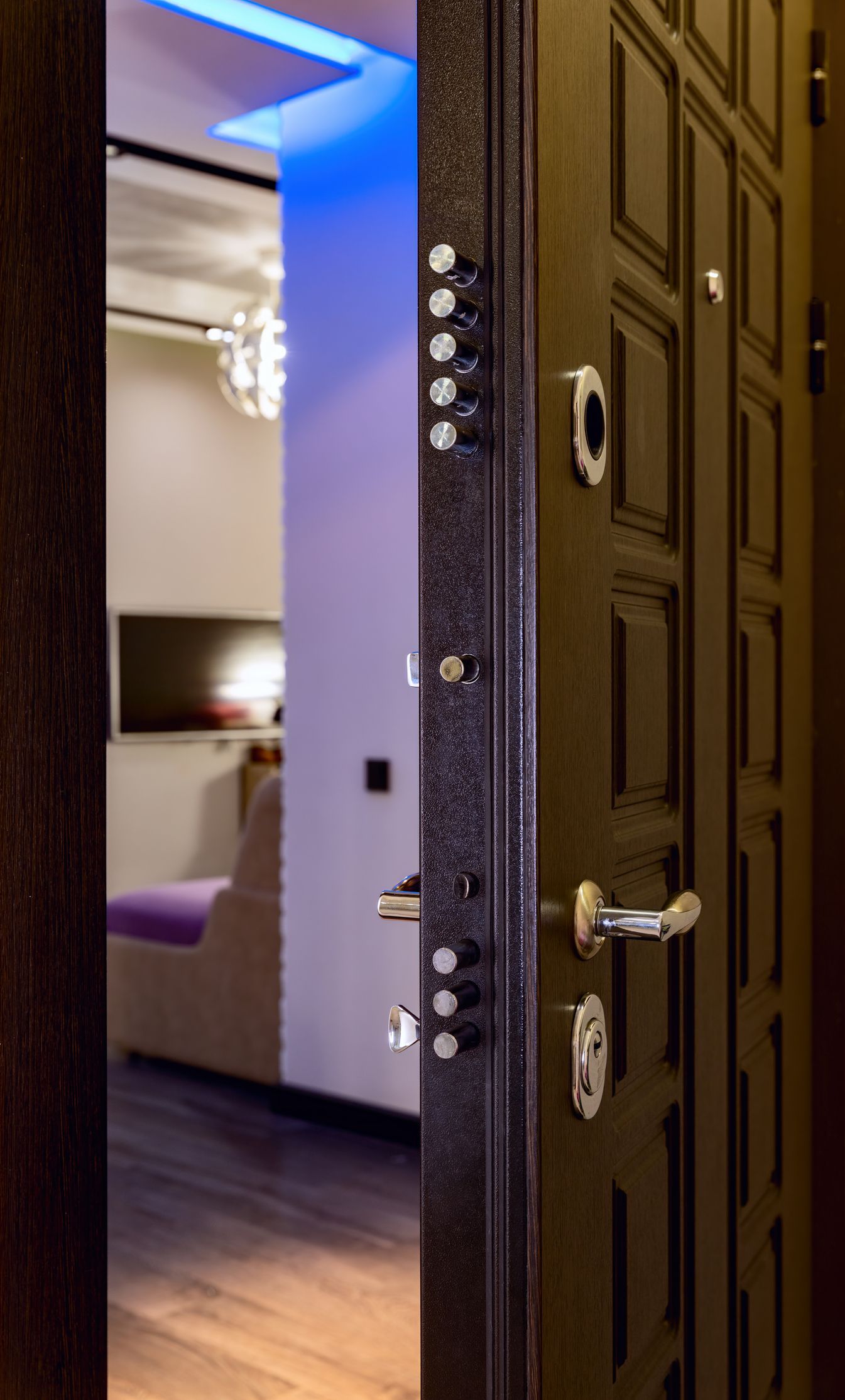 Apri la porta di sicurezza nera e scopri l'interno di un appartamento con mobili e illuminazione blu.