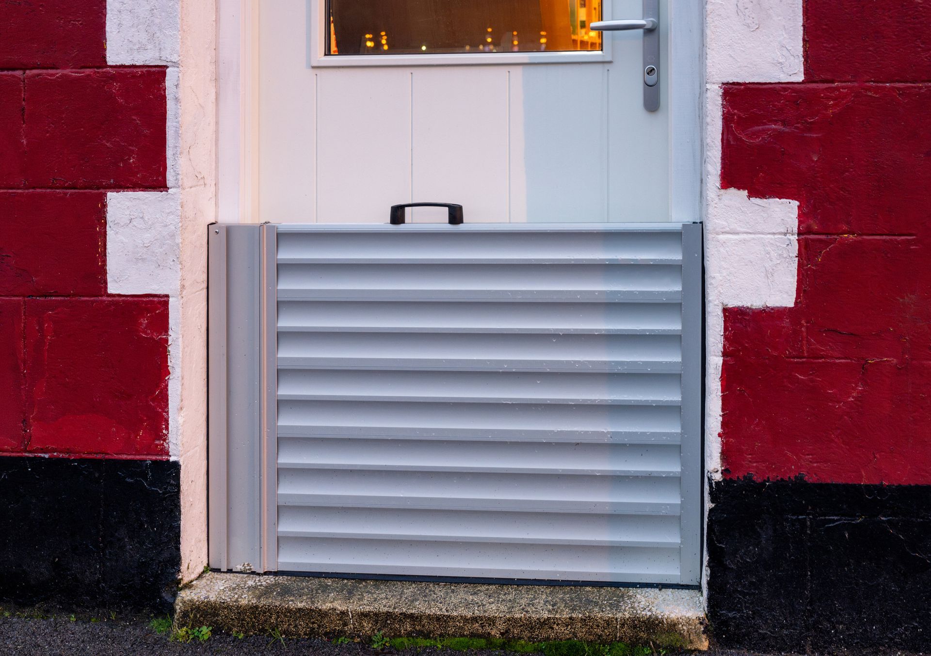 Barriera anti-inondazione installata sulla soglia di un edificio in mattoni rossi.