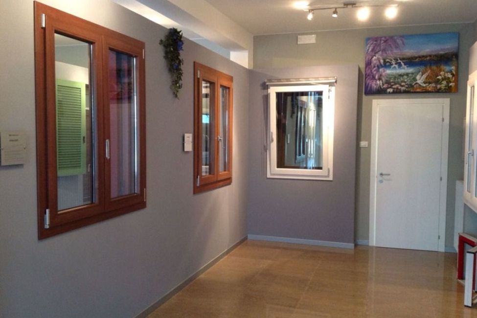 Vetrine di uno showroom; cornici in legno e bianche su pareti grigie, pavimento in legno chiaro, pittura.