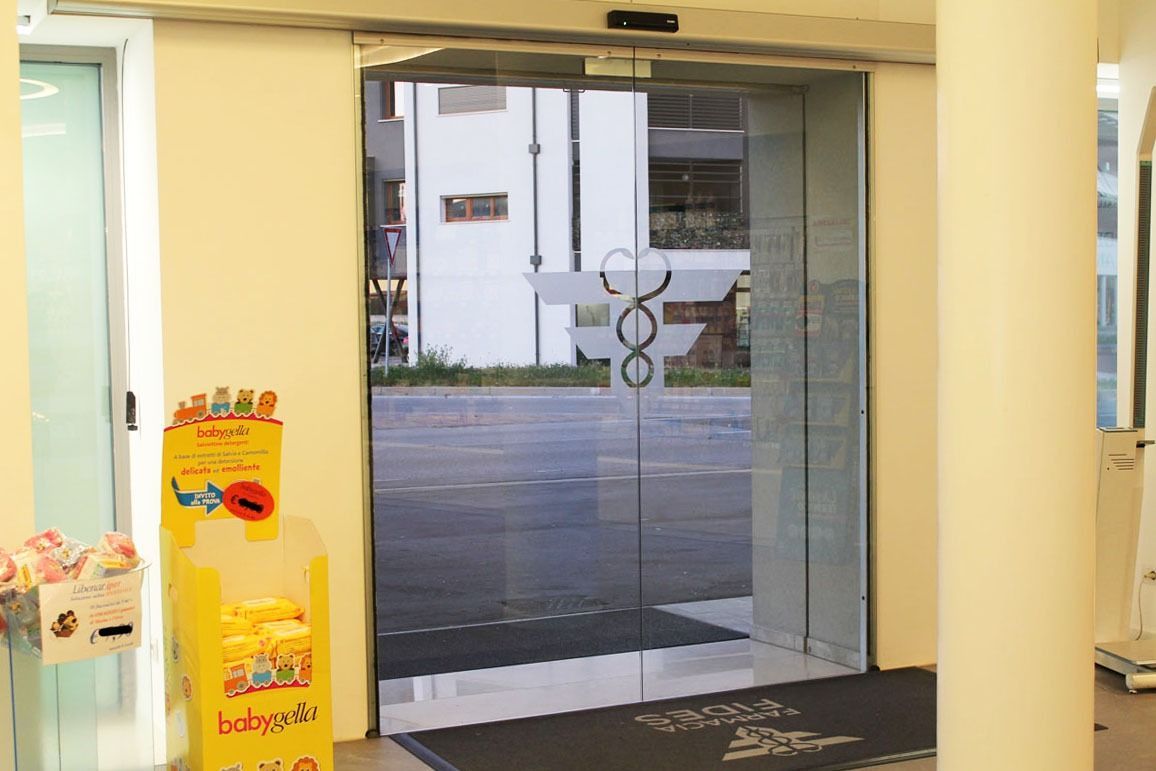 Porte d'ingresso in vetro, automatiche, che conducono all'esterno; espositore giallo sulla sinistra.
