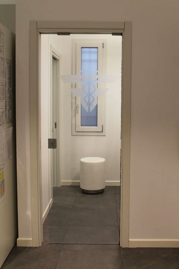 Porta che conduce a una piccola stanza con una finestra, un design smerigliato e uno sgabello bianco.