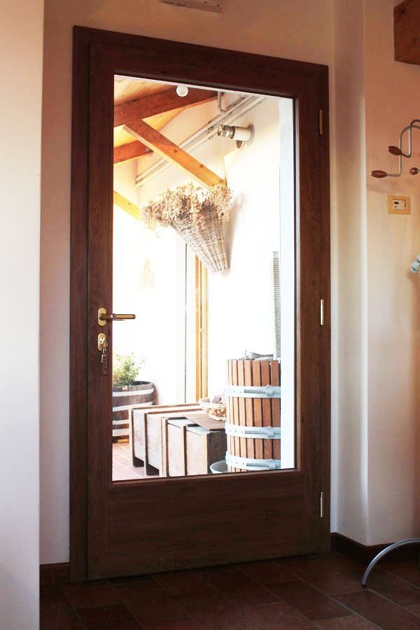 Porta in vetro con cornice marrone che conduce a un'area esterna con oggetti in legno impilati e un lampadario decorativo.
